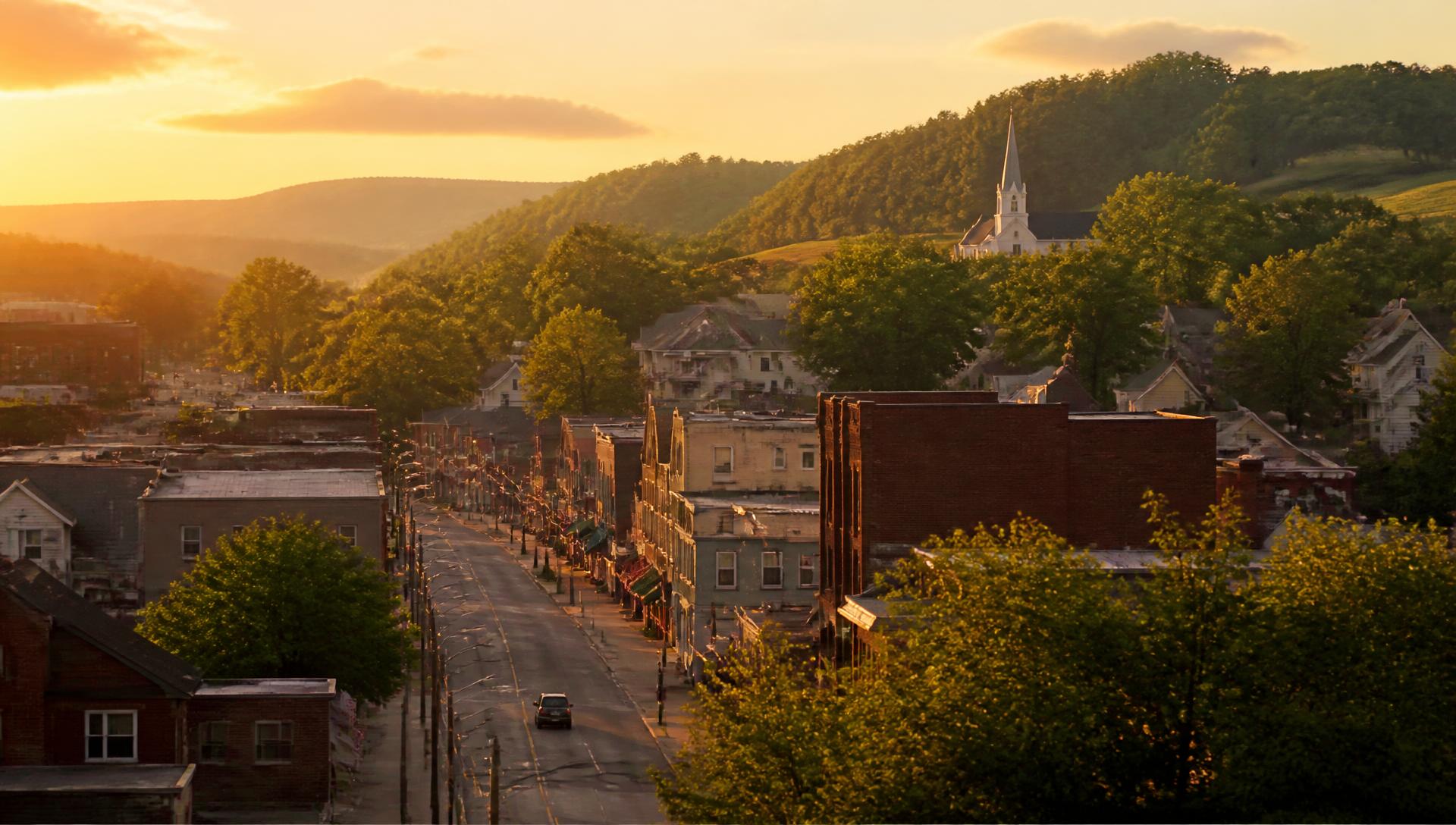 Aerial view of a small Ohio town at golden hour with a church steeple and green hills